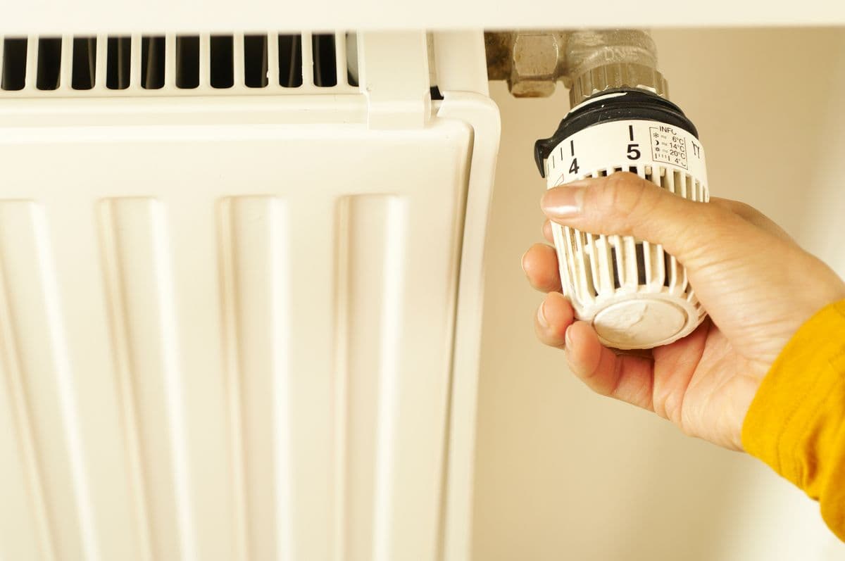 Hand adjusting a home thermostat to control temperature